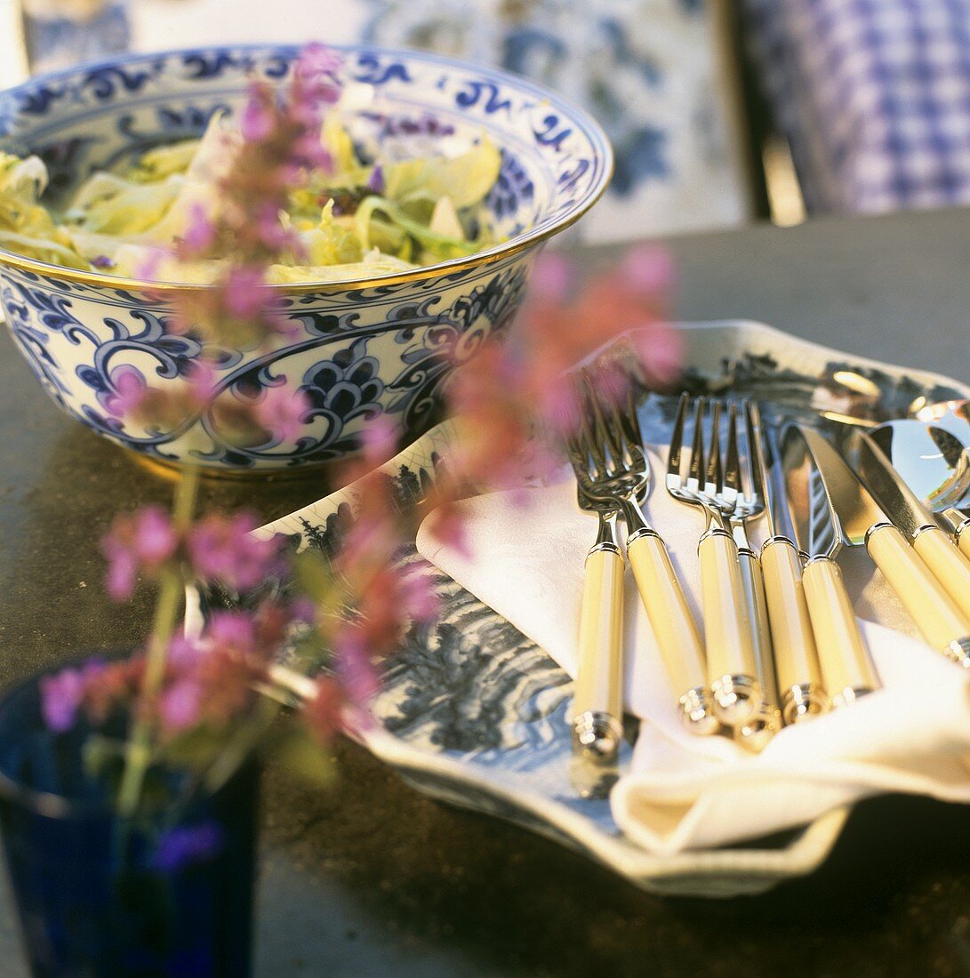 Cutlery, mixed salad leaves behind