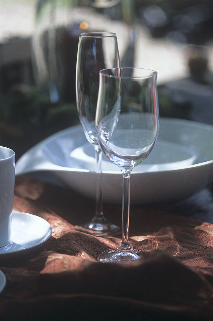 Wein- und Sektglas vor weissesm Geschirr auf einem Tisch