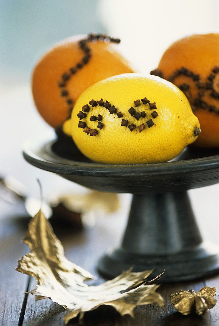 Mit Nelken gespickte Orangen und Zitrone in einer Schale