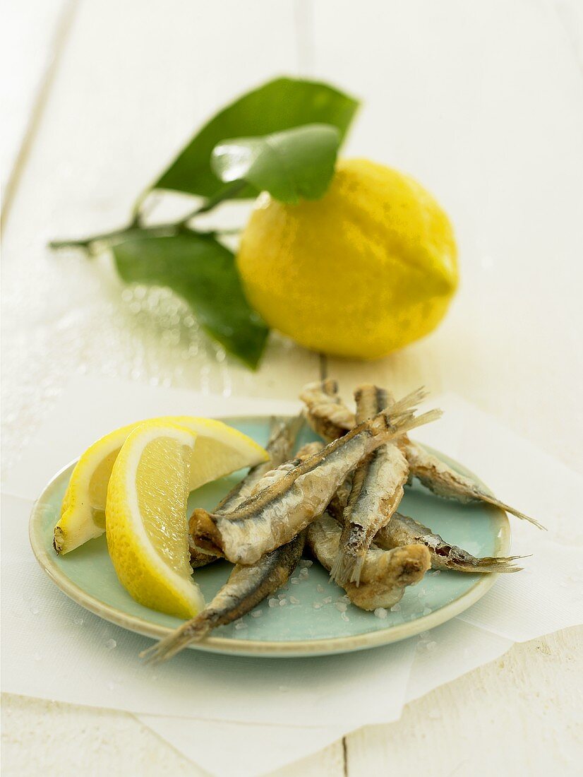Deep-fried sardines with lemon wedges