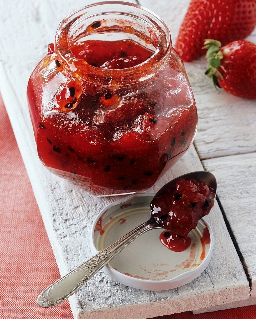 Erdbeer-Maracujamarmelade in Glas und auf einem Löffel