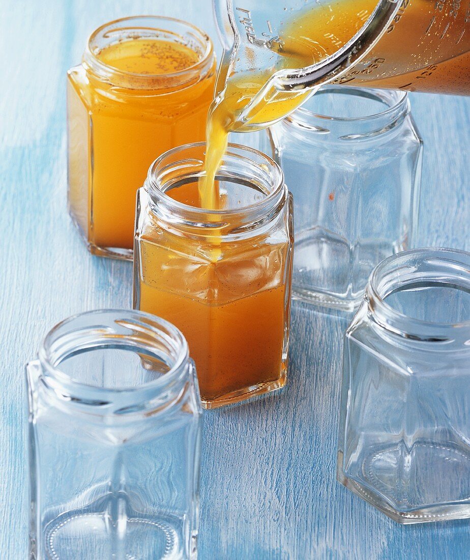 Orangen-Campari-Gelee wird in Marmeladengläser gefüllt