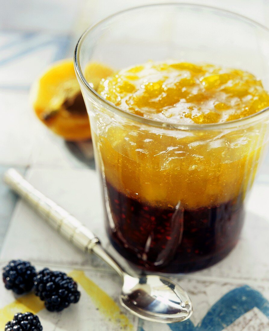 Blackberry and apricot jam layered in a glass