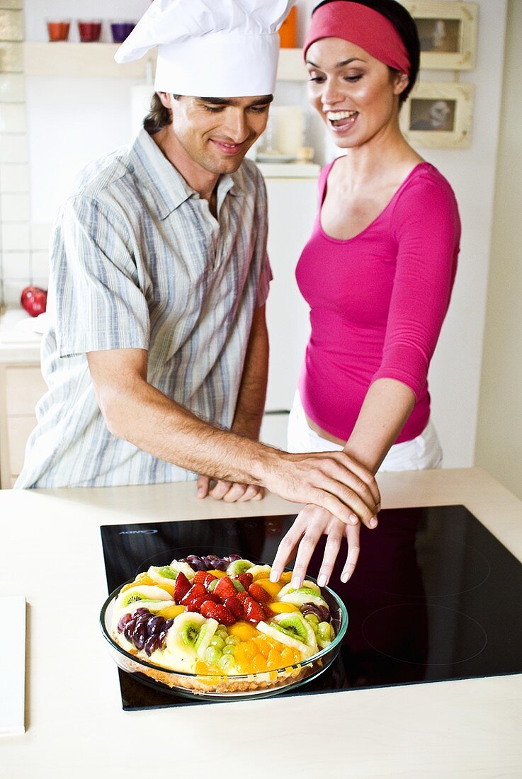 Mann hält Frau davon ab vom Obstkuchen zu naschen