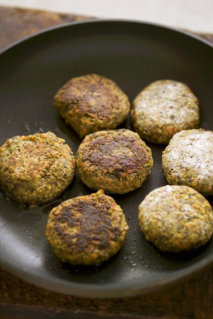 Lentil burgers being fried in a frying pan
