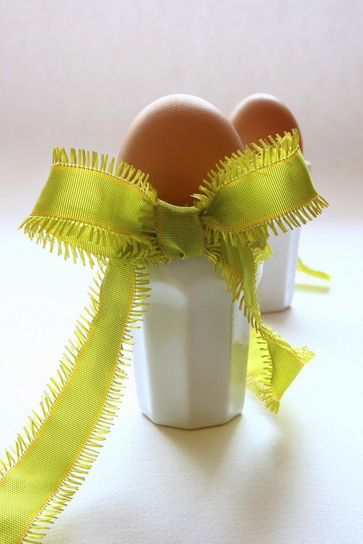 Two boiled eggs in eggcups decorated with bow