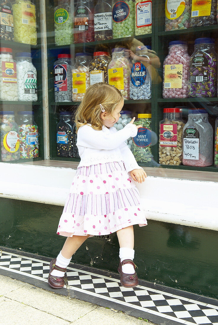 Little girl outside a sweetshop in Rye, Sussex, England