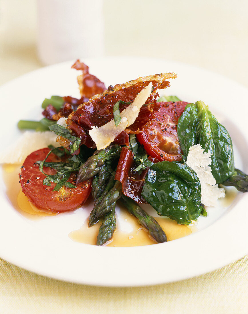 Green asparagus, spinach and tomato salad with fried bacon