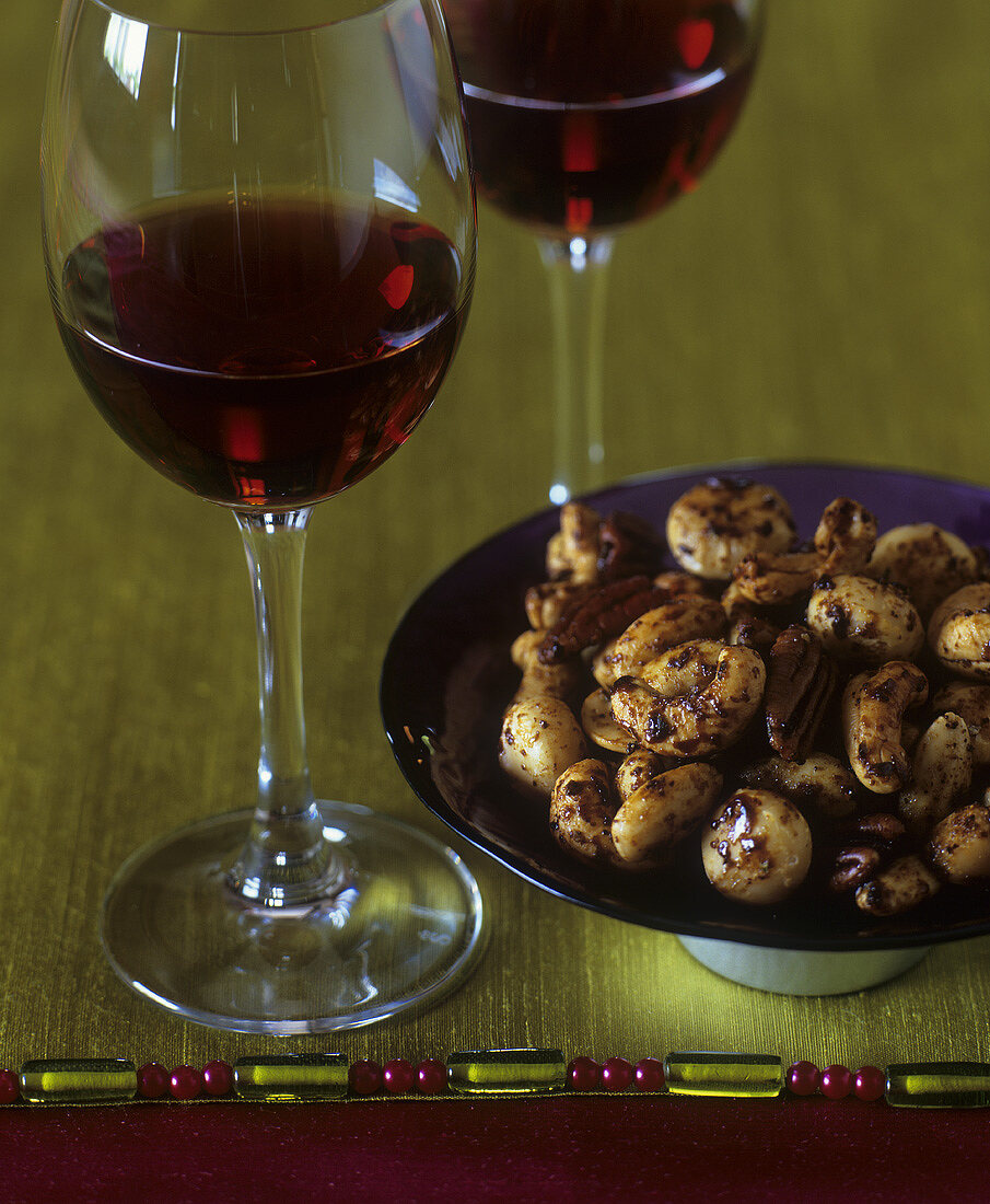 A small dish of roasted nuts and two glasses of red wine