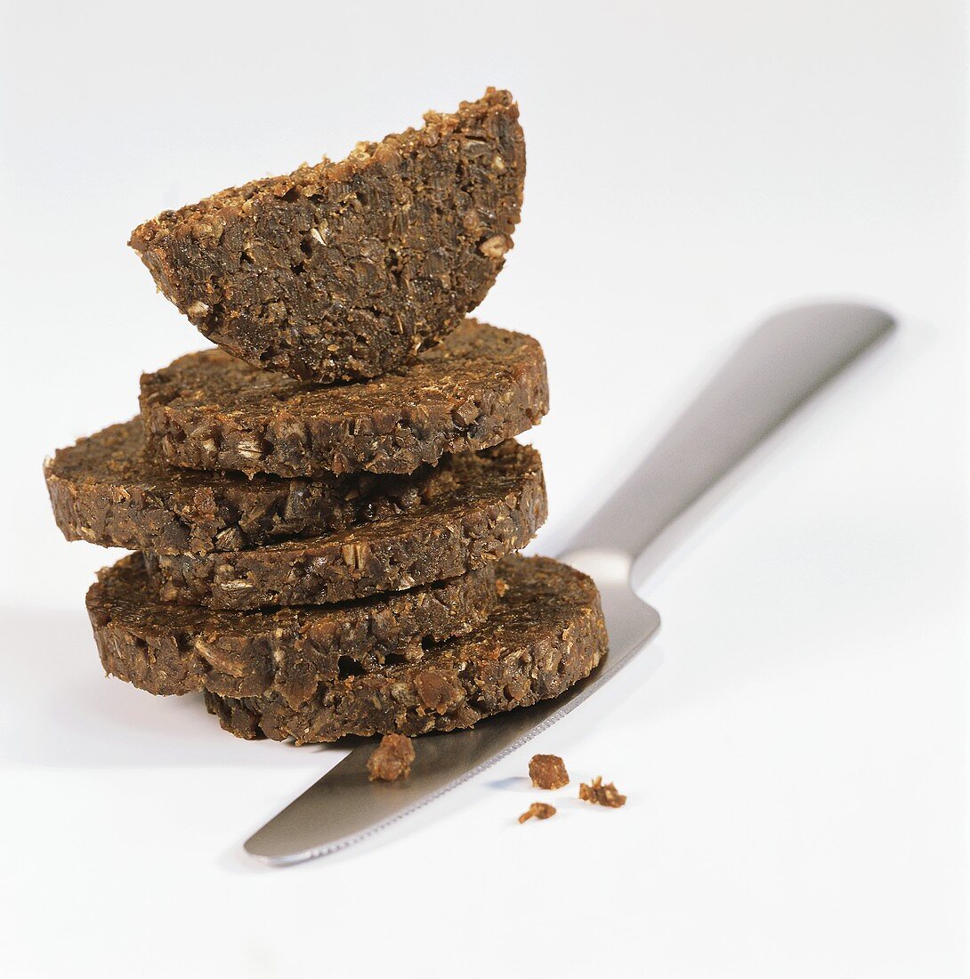 Slices of pumpernickel, in a pile with knife