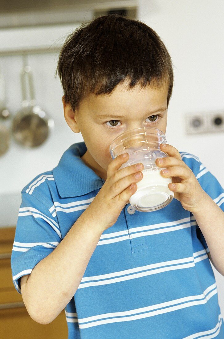 Kleiner Junge trinkt Milch aus dem Glas