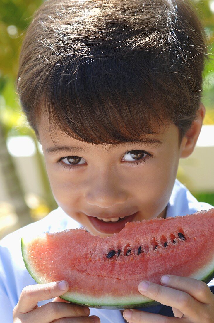 Small boy biting into a slice of watermelon