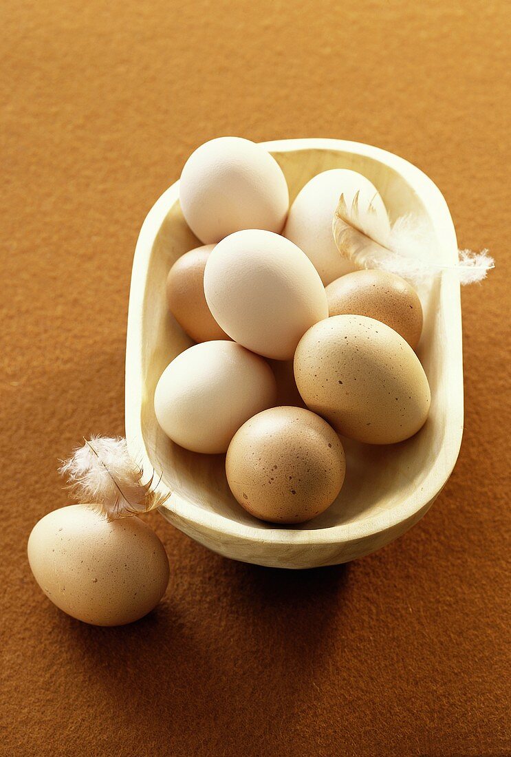 White and brown hen's eggs in a wooden bowl