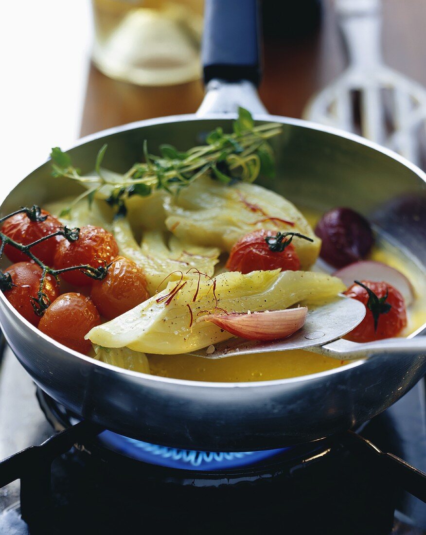 Fennel and tomatoes in saffron broth in a frying pan