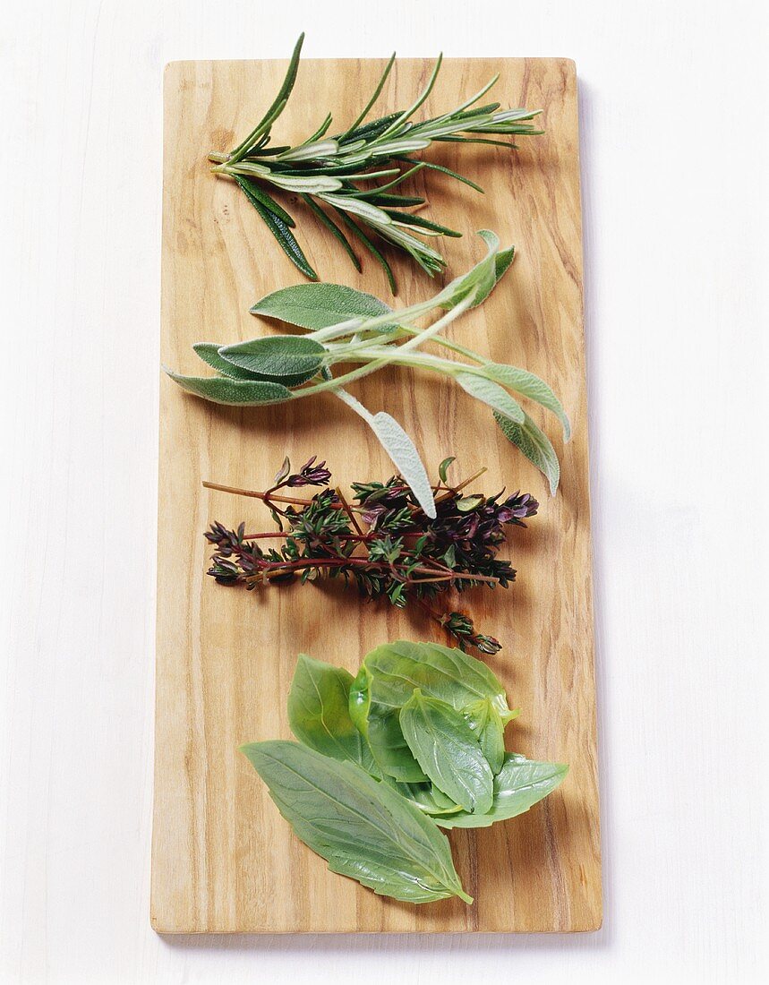 Basil, thyme, sage and rosemary on wooden board