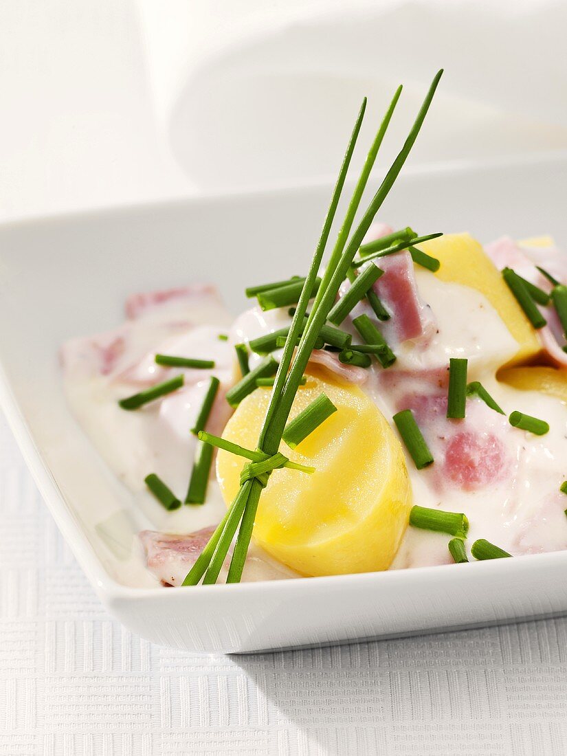 Potatoes with ham and sour cream sauce and chives