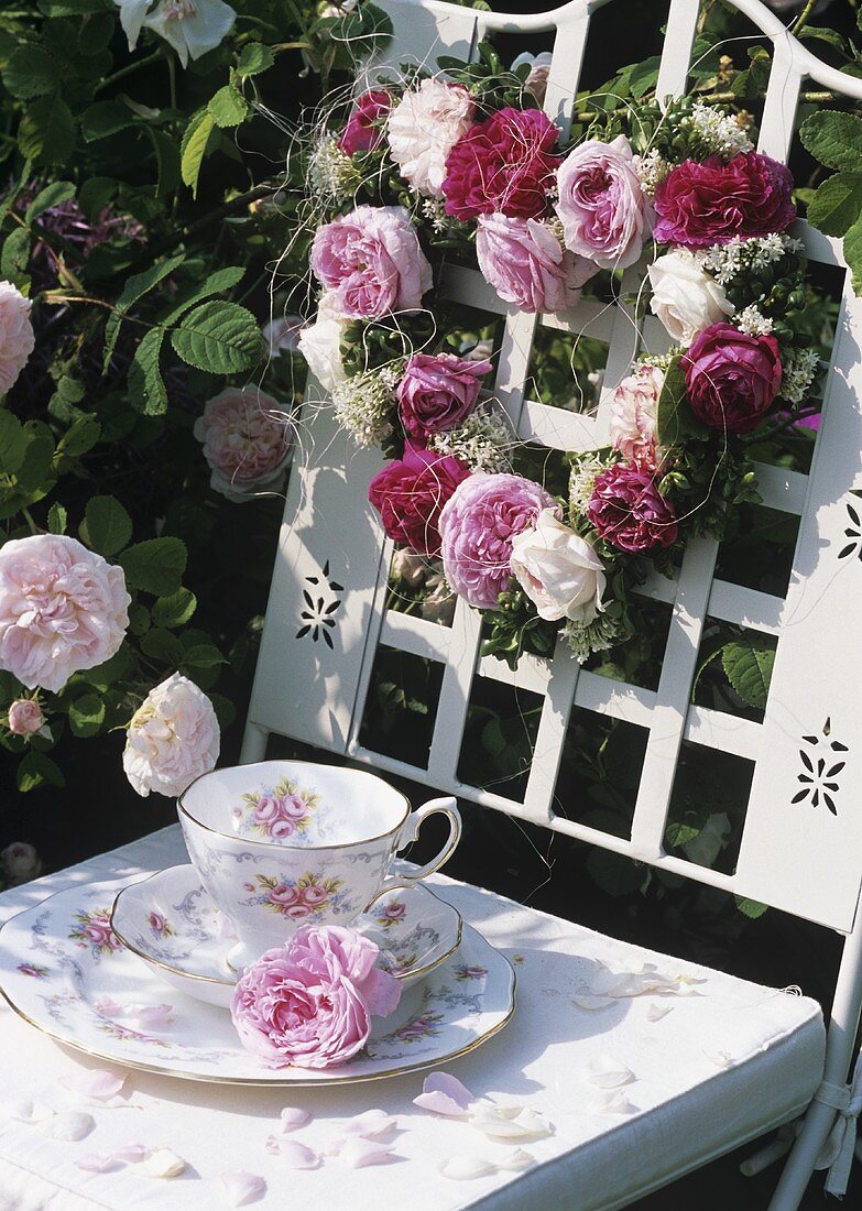 Rose-patterned coffee things and heart of roses in garden