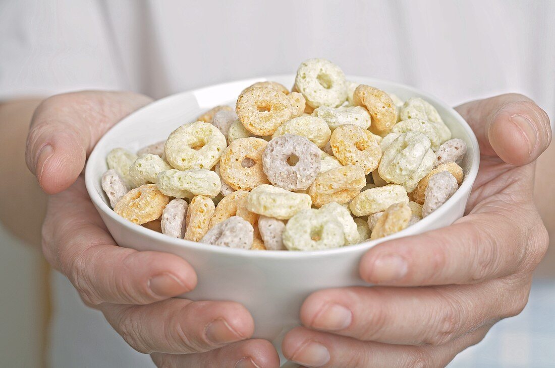 Hands holding a bowl of cereal rings