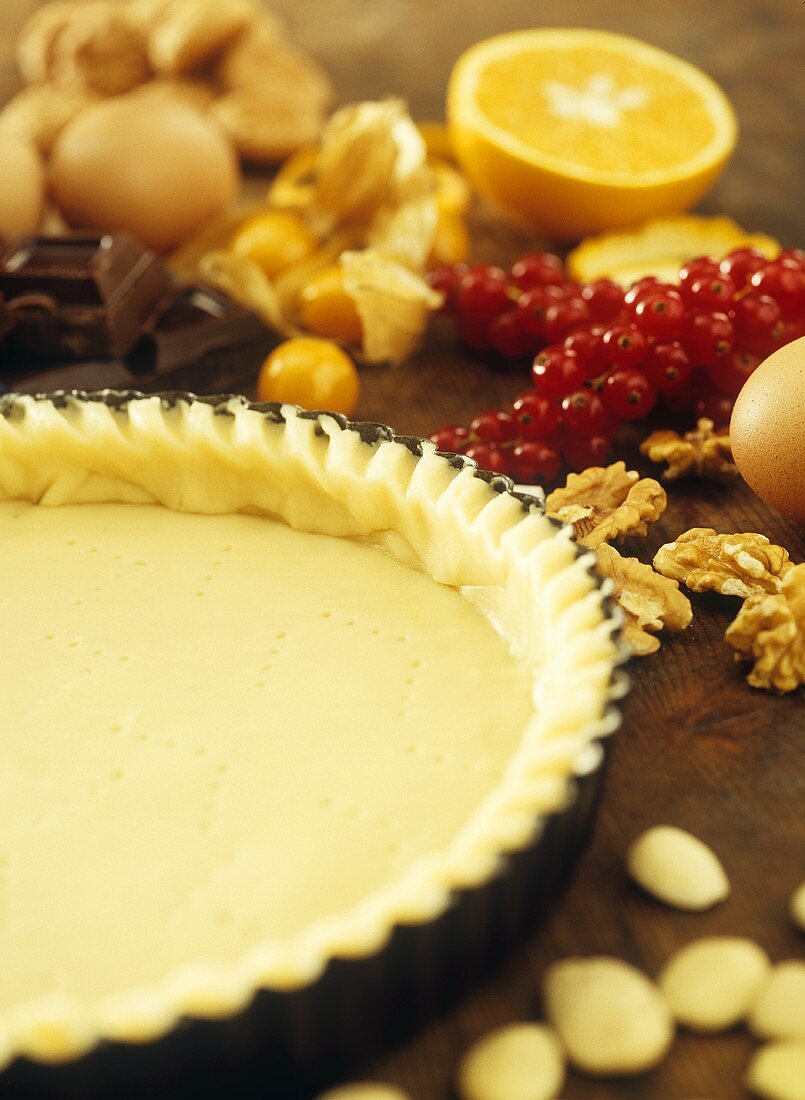 Pastry in a tart tin surrounded by baking ingredients