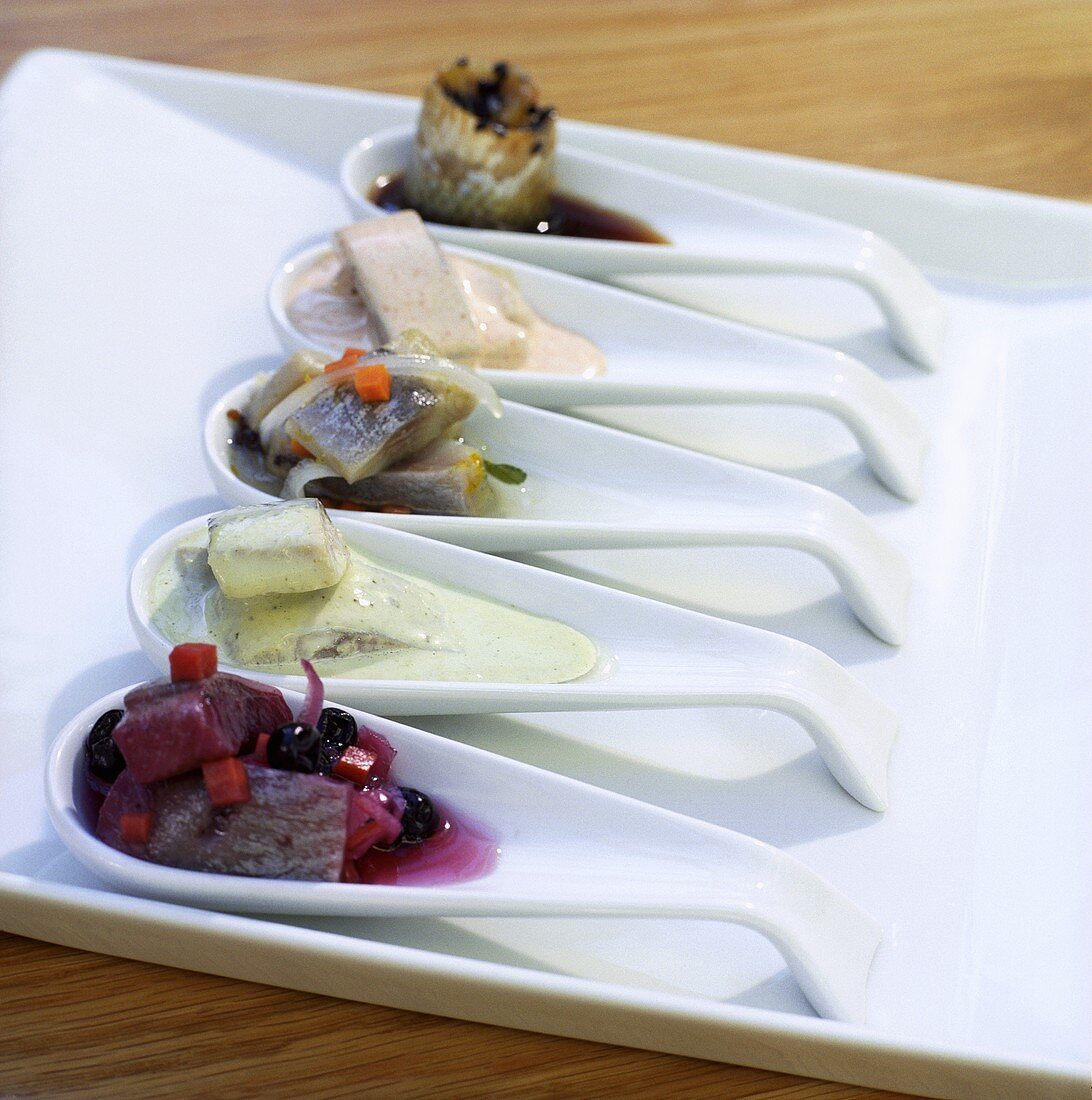 Assorted herring appetisers on china spoons
