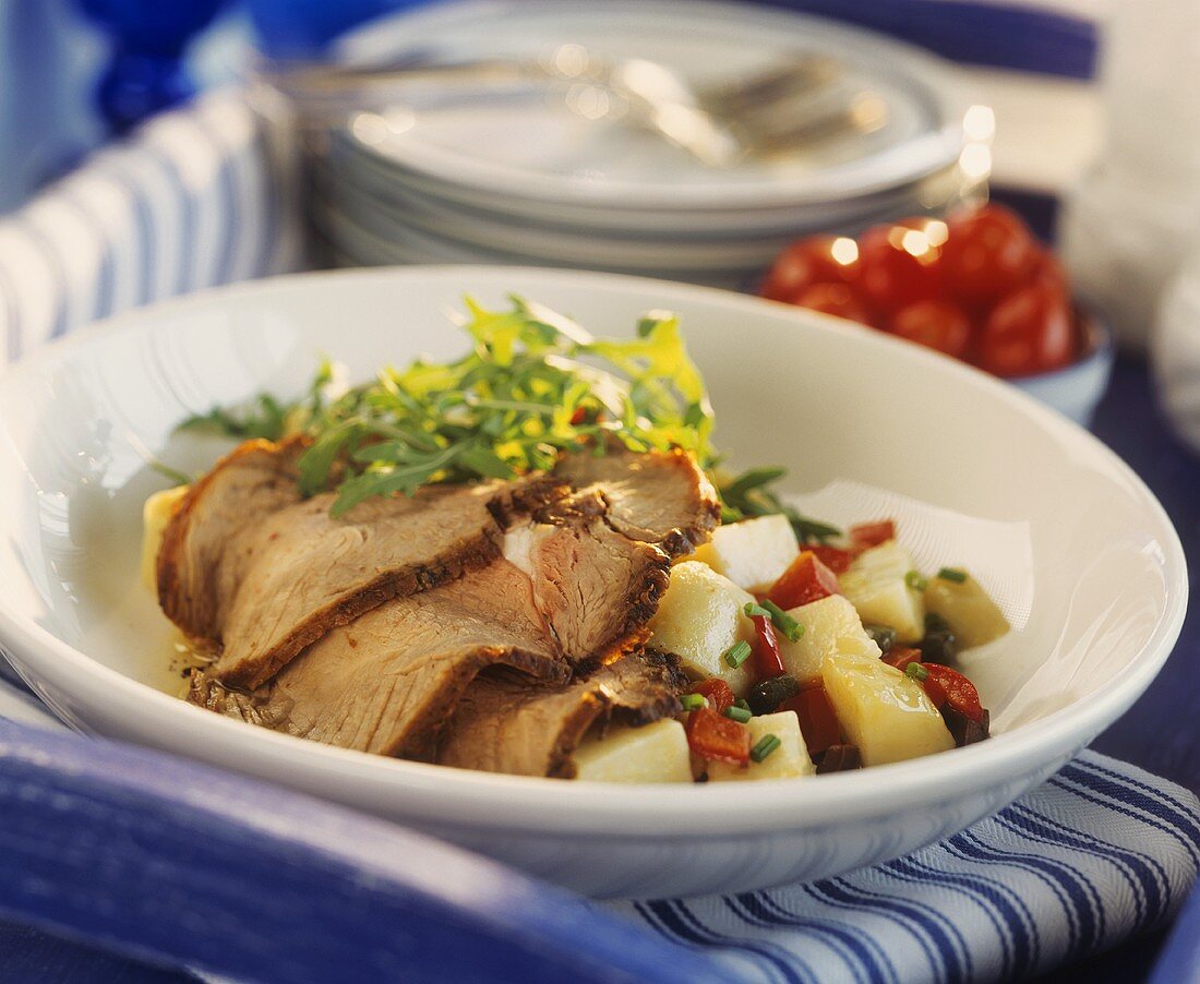 Slices of roast veal on potato and pepper salad