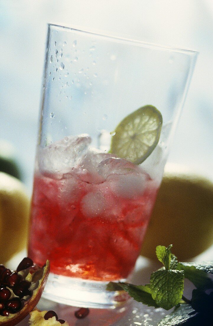 Pomegranate juice with ice cubes & slice of lime in glass
