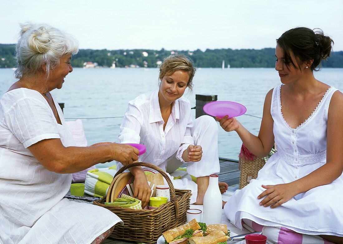 Drei Frauen auf einem Bootsteg packen Picknickkorb aus
