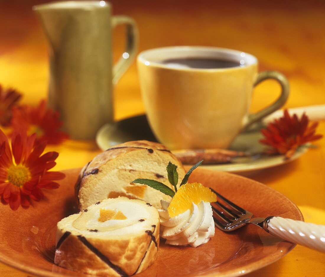 Orangen-Sahne-Biskuitrolle und eine Tasse Kaffee