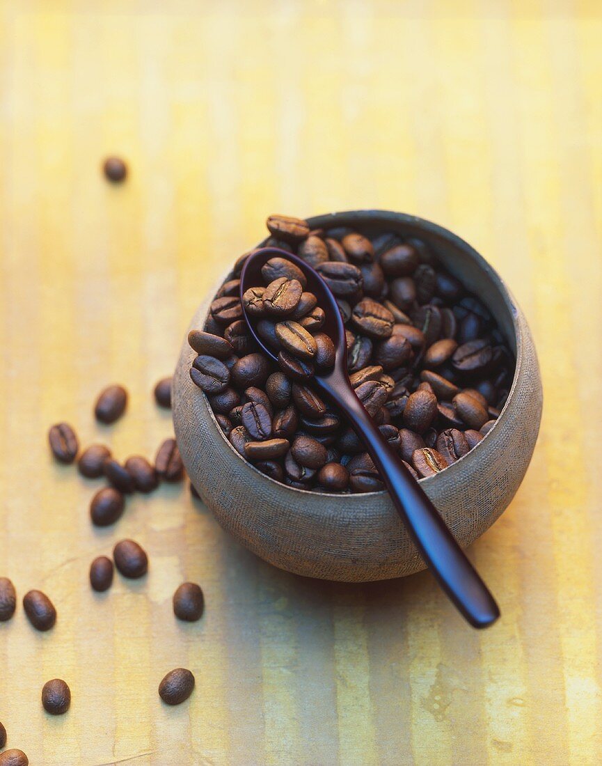 Kaffeebohnen in einer rostbraunen Schale und auf Löffel