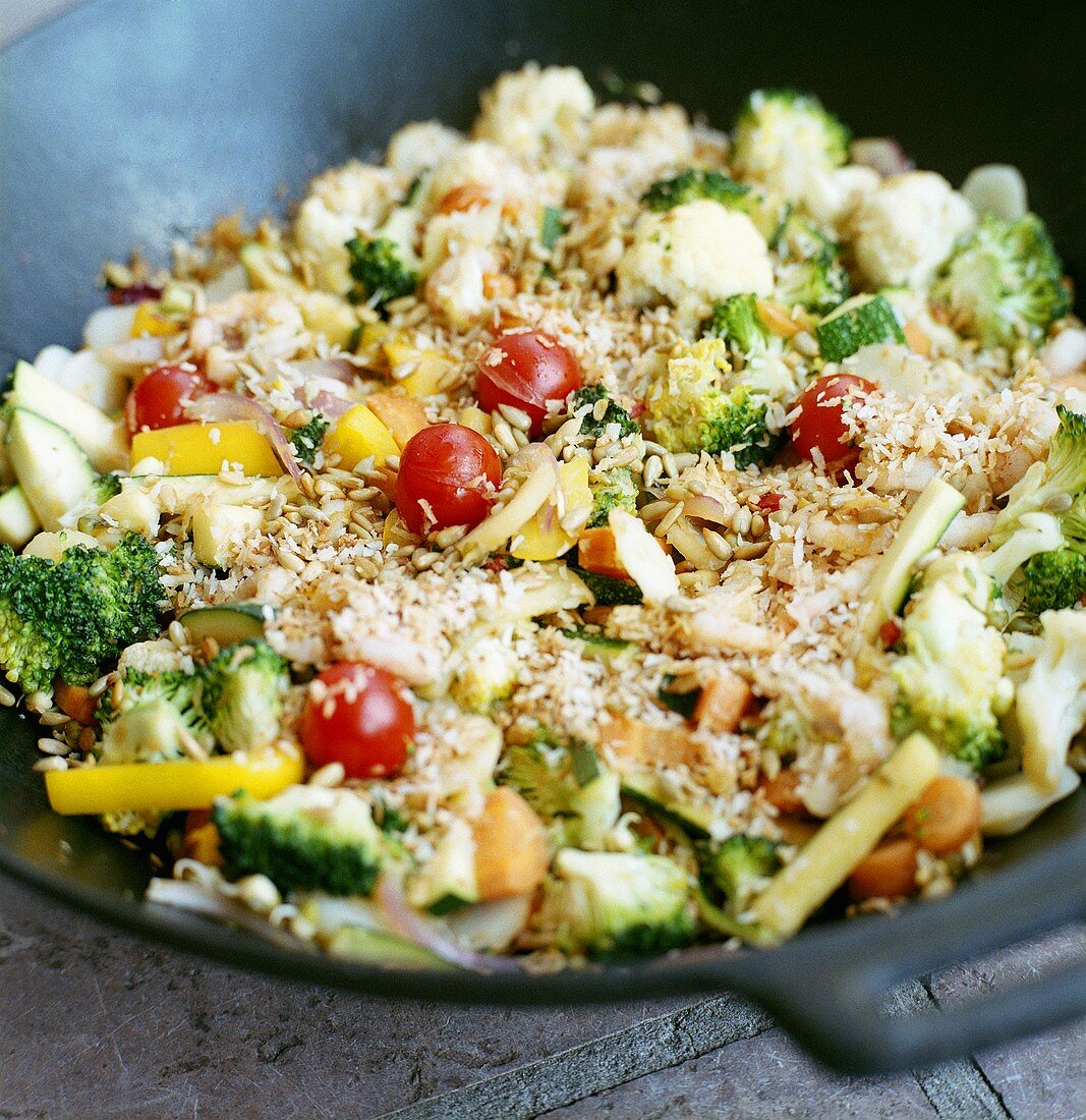 Vegetables, shrimps, grated coconut, sunflower seeds in wok