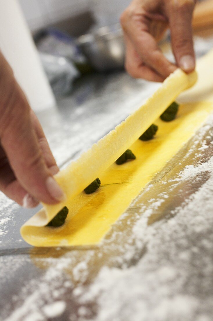 Making spinach ravioli (folding pasta dough over filling)