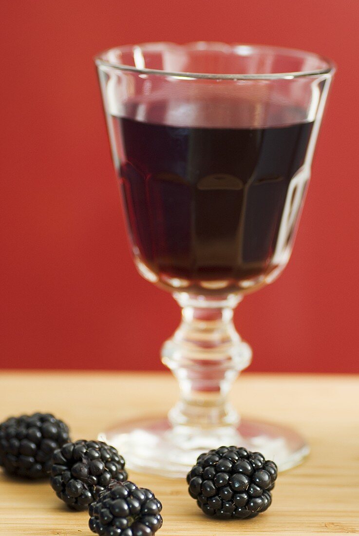 Glass of red wine with subtle blackberry note, fresh blackberries