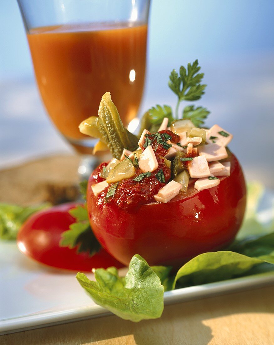 Gefüllte Tomate, im Hintergrund ein Glas Tomatensaft