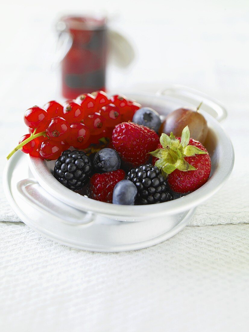 Fresh berries, a jar of berry jam in background