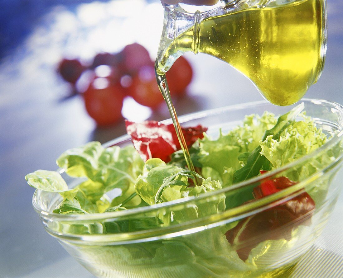 Pouring oil over salad leaves