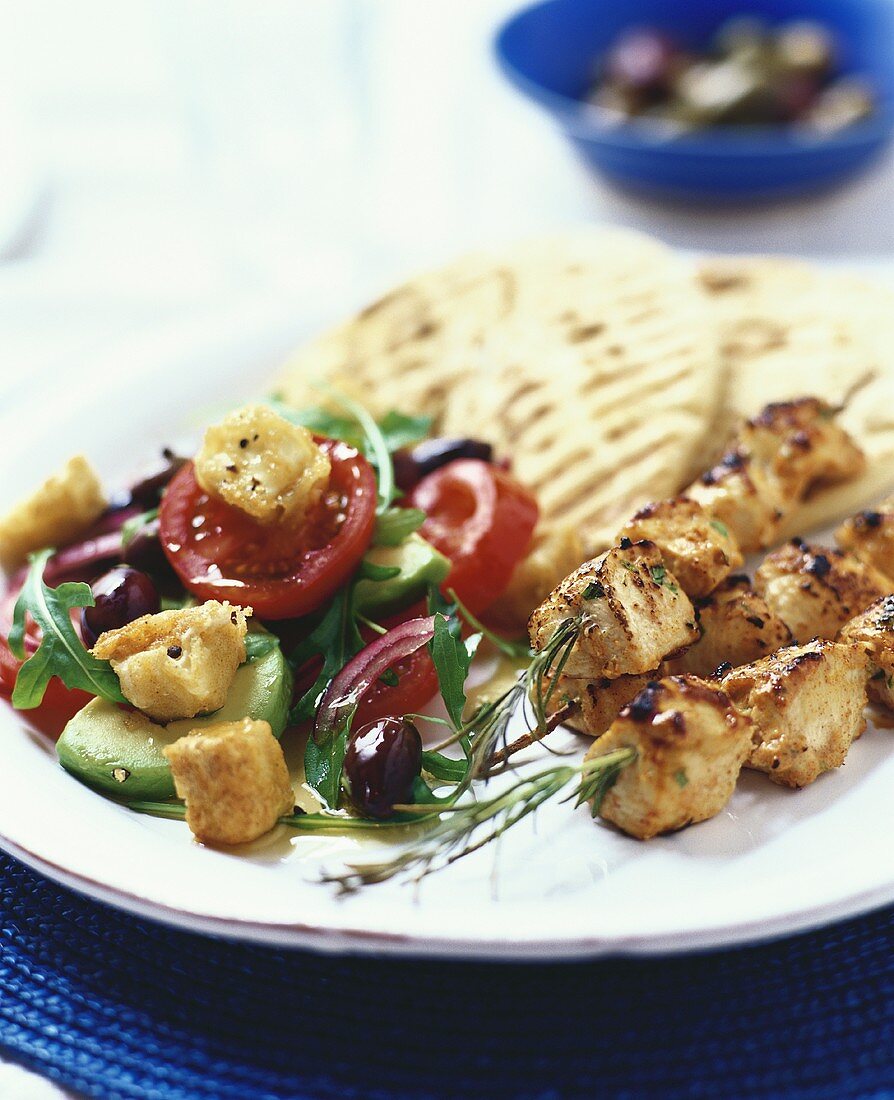 Chicken skewers with vegetable salad and pita bread