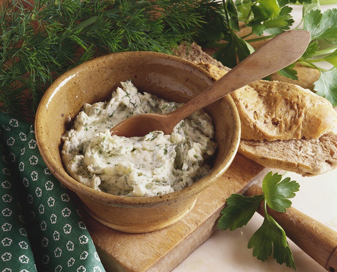 Herb butter in a bowl with a wooden spoon