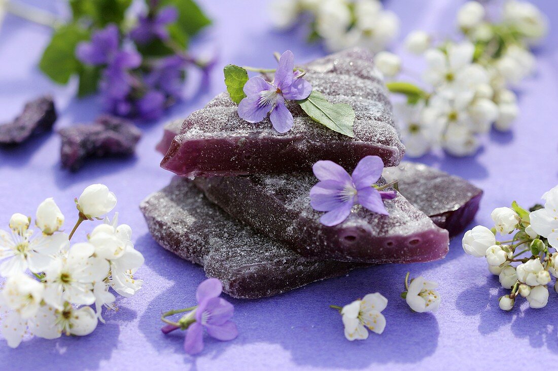 Violet sweets with violets and sprigs of blossom