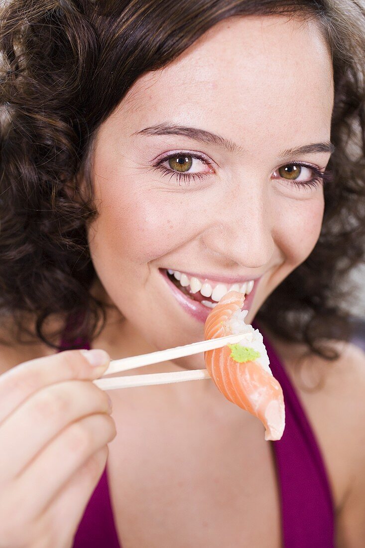 Woman eating sushi with chopsticks