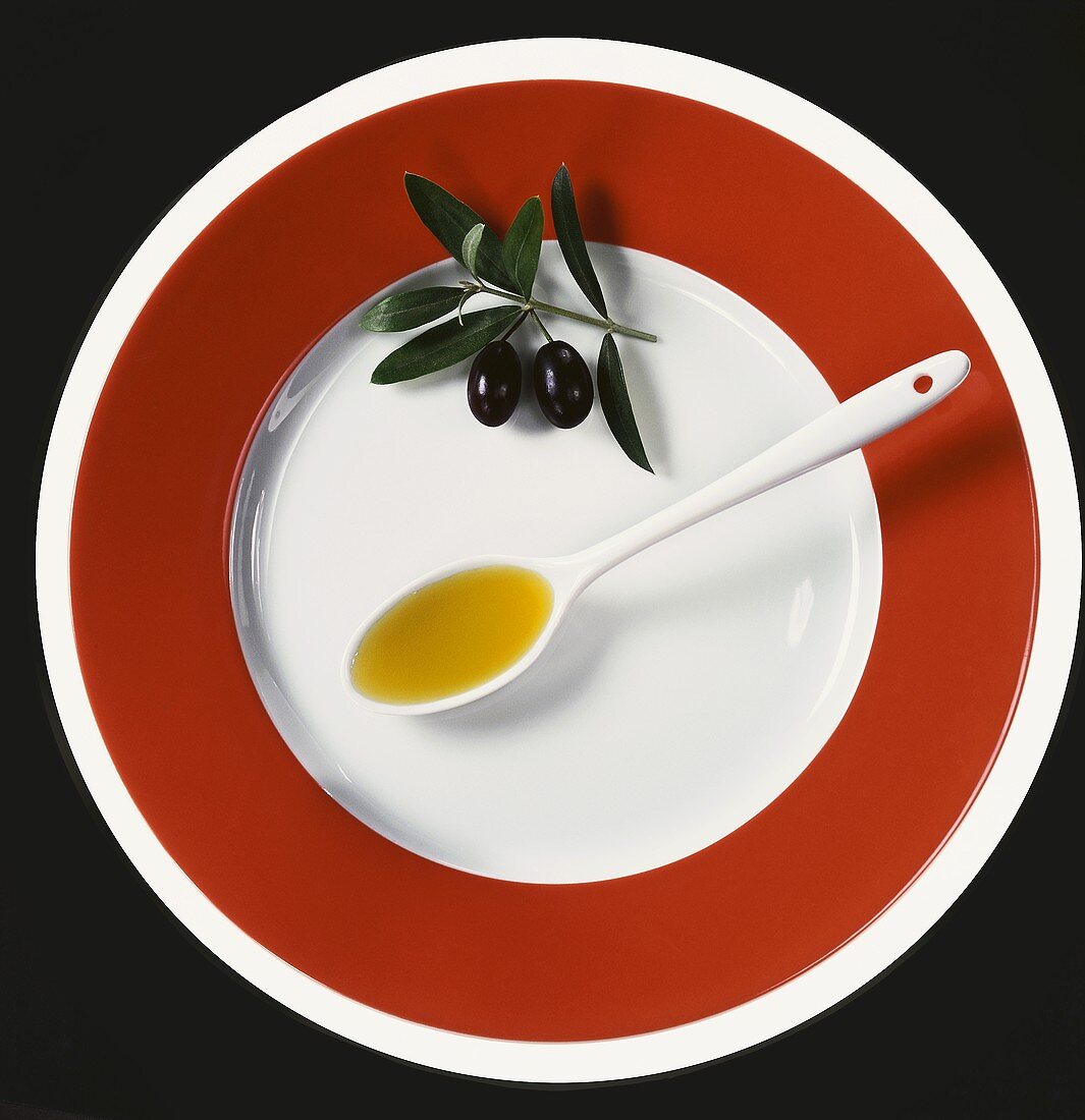 Olive oil in spoon with olives on olive sprig