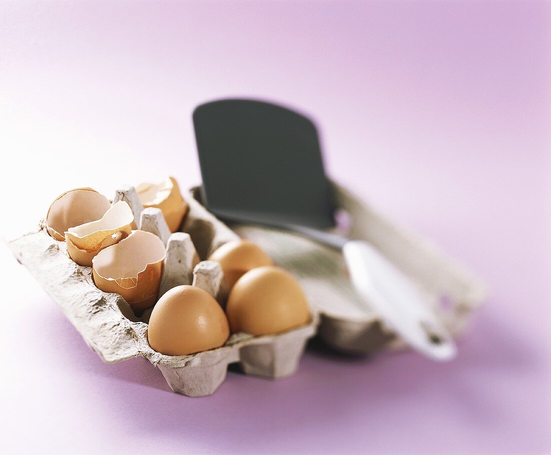 Three whole eggs and eggshells in an egg box