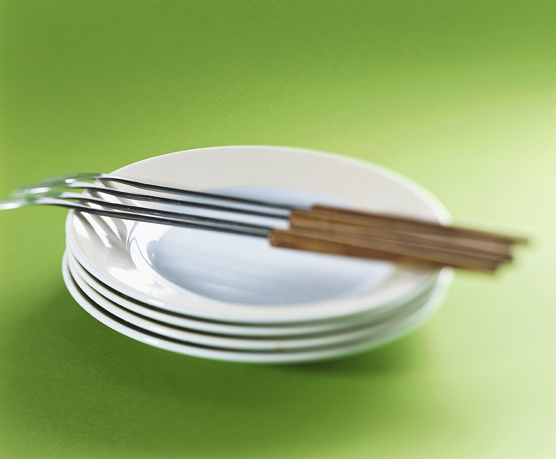 A pile of plates with fondue forks