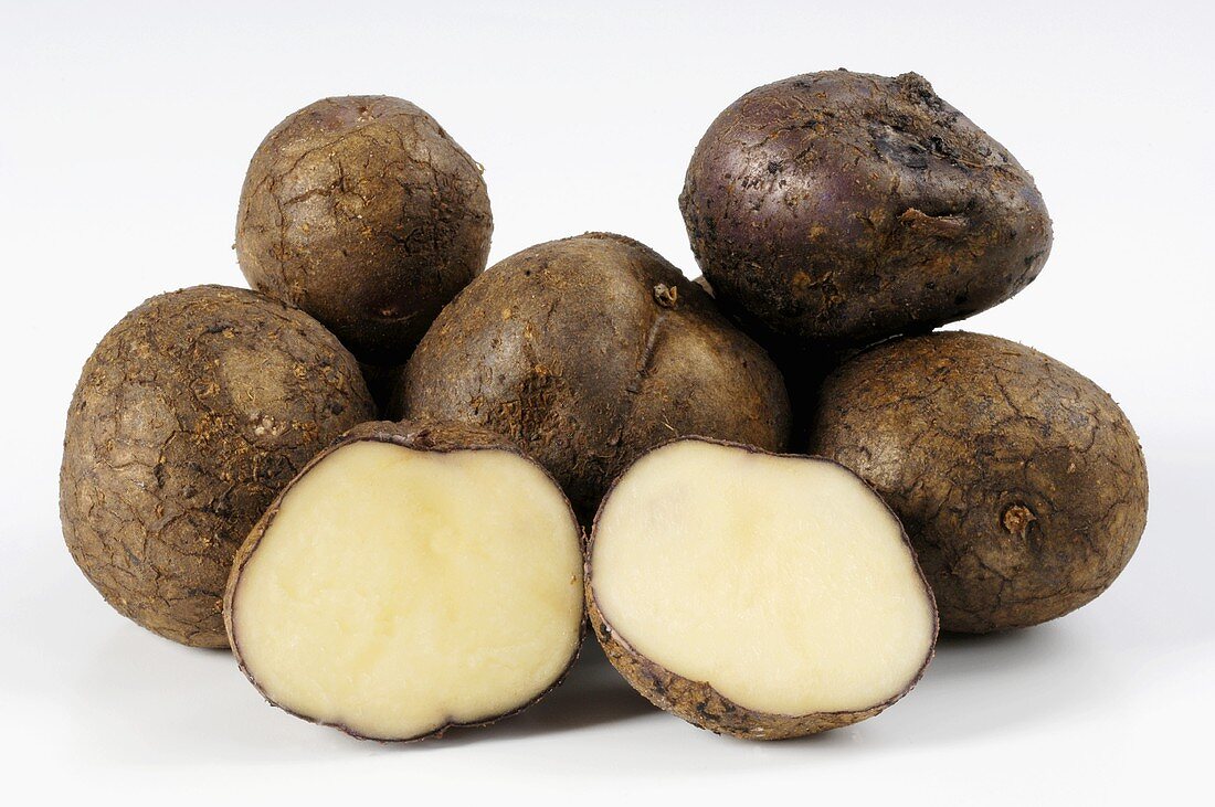 Mehrere Kartoffeln der Sorte 'Odenwälder Blaue' ganz und halb