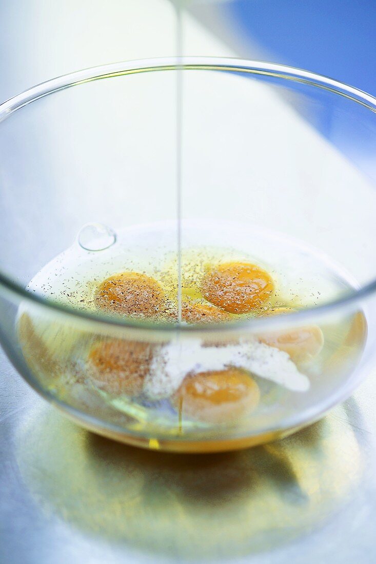 Pouring cream onto eggs broken into a bowl