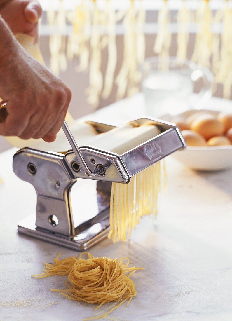 Running pasta dough through a pasta maker