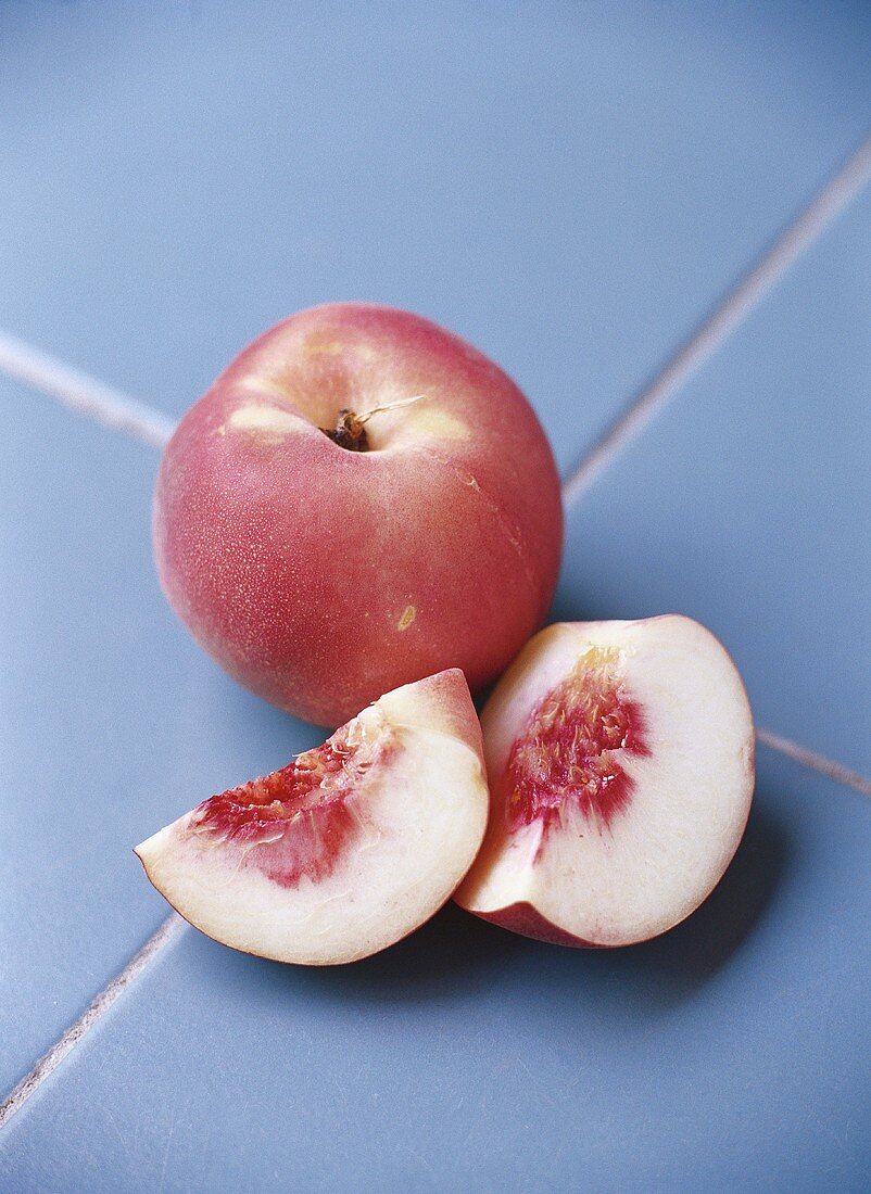 One whole white peach and one cut into pieces