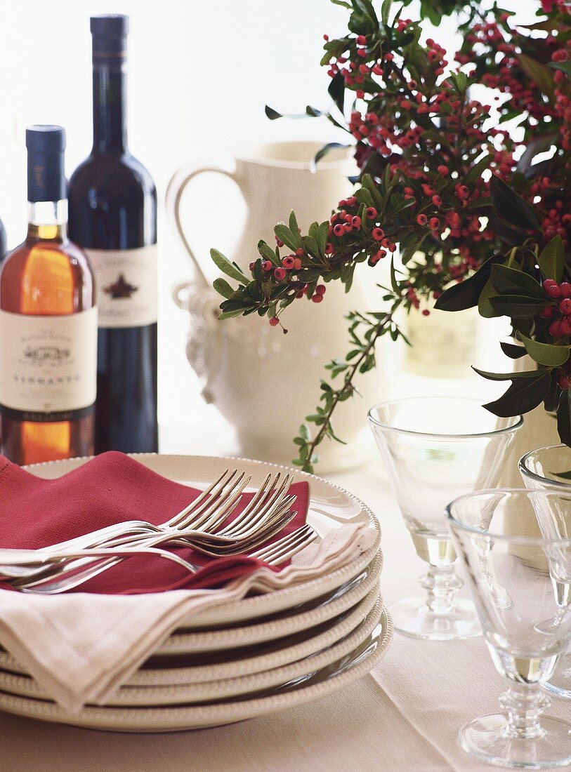 Tisch mit Tellerstapel, Besteck und Wein