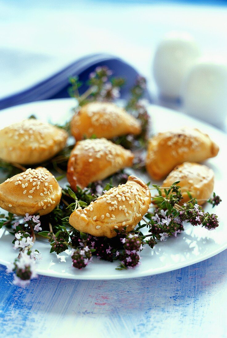 Several pierogi (small pasties) and thyme on a plate