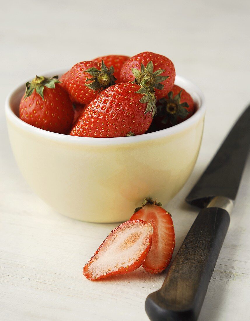 Erdbeeren in der Schale mit halbierter Erdbeere und Messer