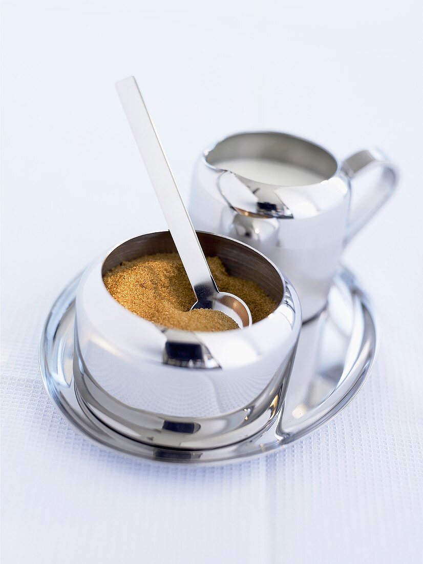 Brown sugar in a sugar bowl with milk jug